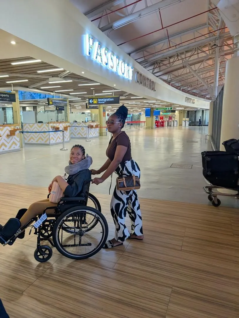 A young person in a wheelchair being helped through an airport