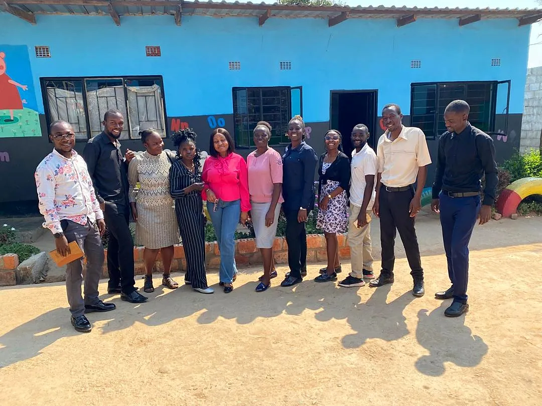 Charis educators and partners standing together outside a brightly painted classroom