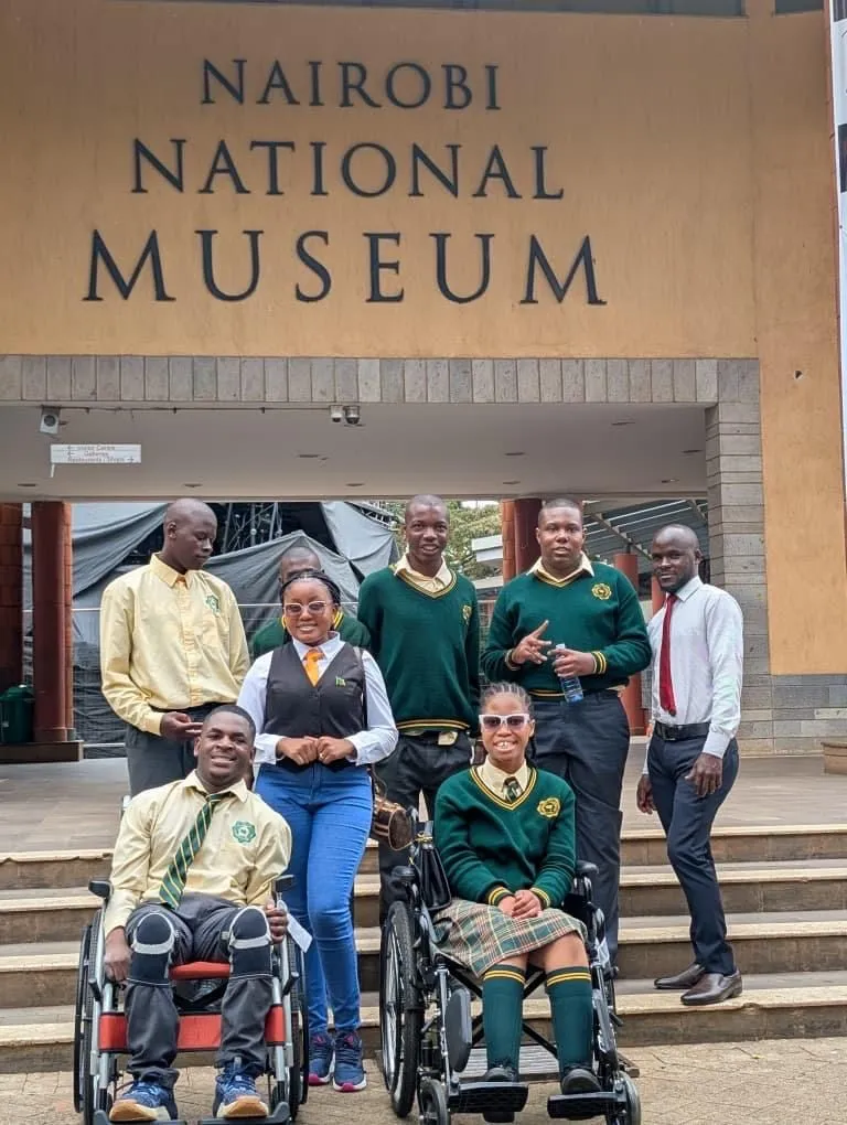 Students, two of them in wheelchairs, with their teachers outside a museum