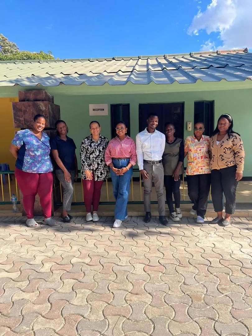 A group of staff smiling together outside a reception building